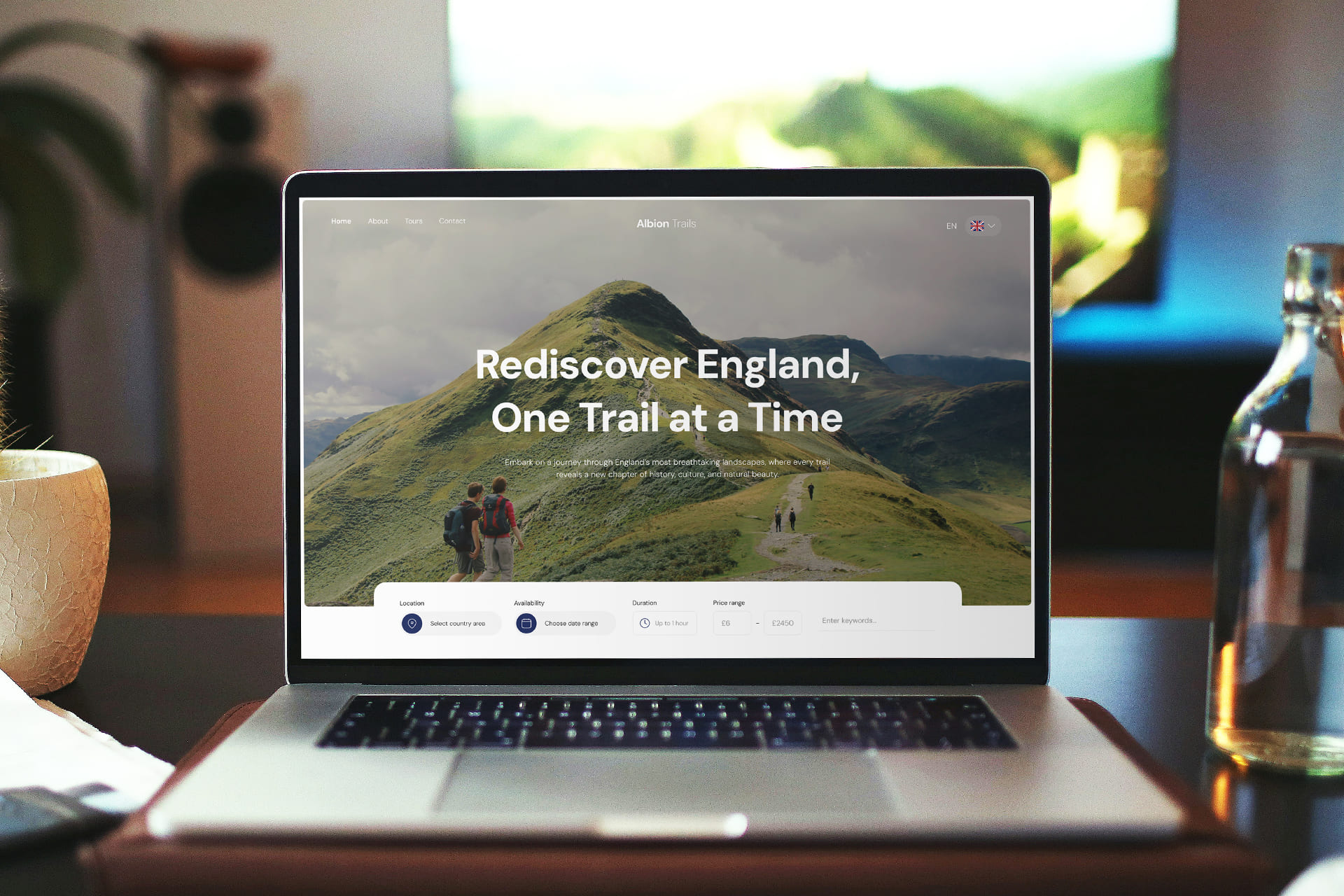 Albion trails - a tour service landing page design project cover image. Laptop displaying a website with a scenic hill and hikers, captioned - Rediscover England, One Trail at a Time. Nearby, a cactus and water bottle. Calm ambiance.